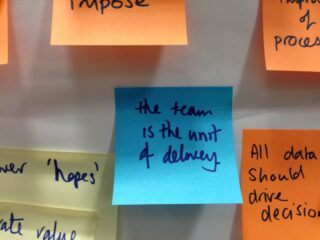 Sticky note saying 'The team is the unit of delivery'